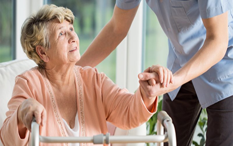 Elderly woman tries to walk with assistance