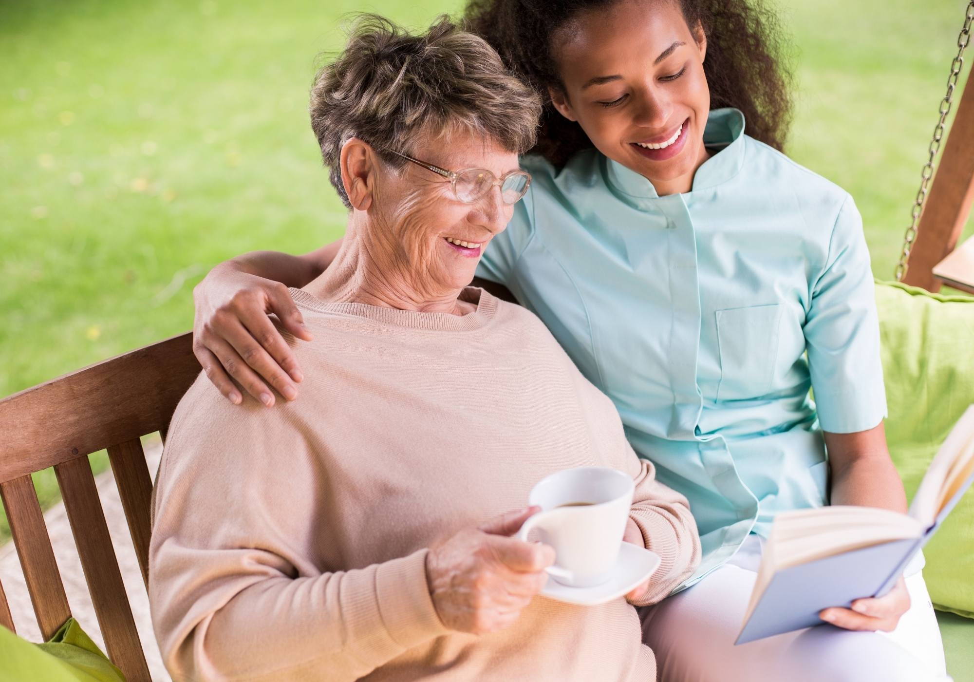 An elderly woman reading a book in the company of a younger woman